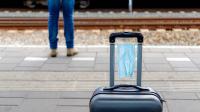 Kuffert står på perron på togstation med mundbind omkring håndtag